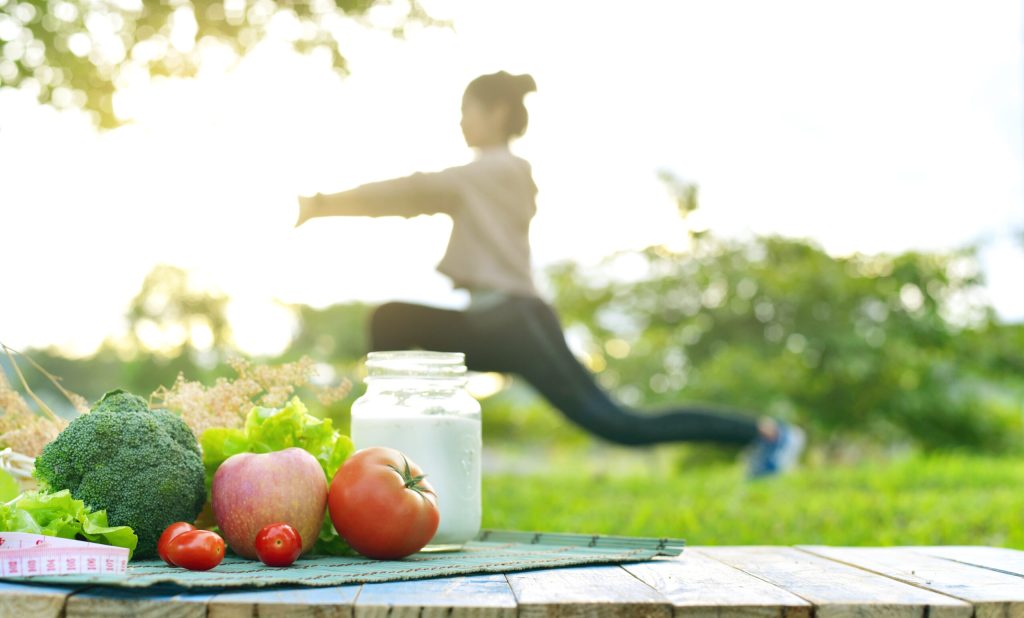 Mulher realizando exercício e frutas disponibilizadas em cima de uma mesa